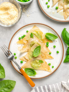 Sweet pea ravioli on a plate with fresh herbs.