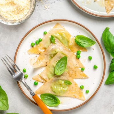 Sweet pea ravioli on a plate with fresh herbs.