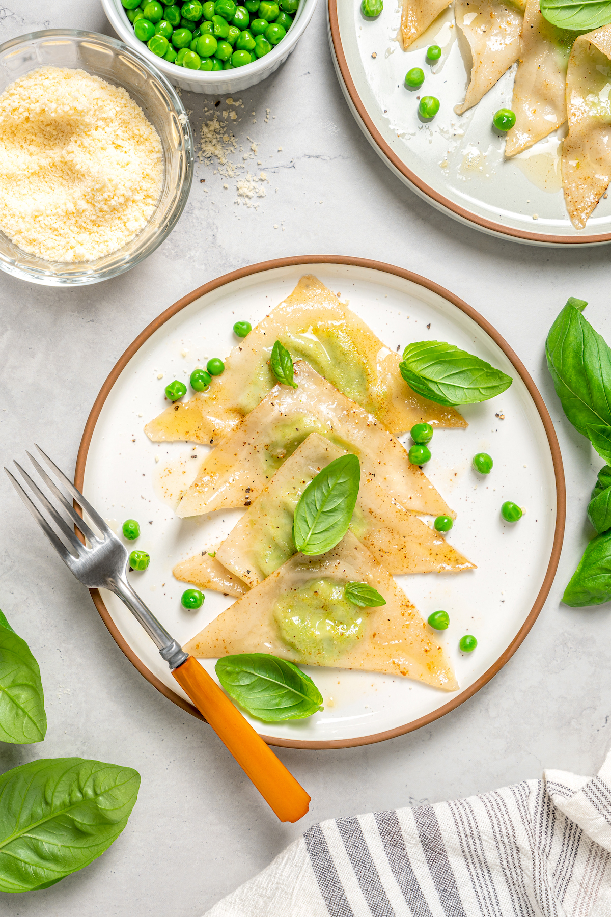 Cheese Ravioli with Peas and Butter Sauce will soon become one of your family's favorites. Easy to make with wonton wrappers! Sweet pea ravioli on a plate with fresh herbs.