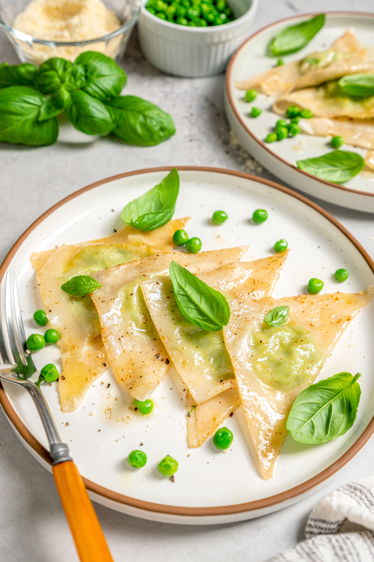 Cheese Ravioli with Peas and Butter Sauce will soon become one of your family's favorites. Easy to make with wonton wrappers! A plate of sweet pea ravioli, garnished with English peas and basil.