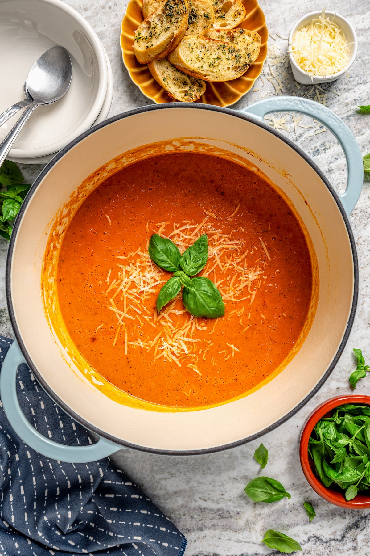This easy tomato bisque recipe with parmesan and Italian seasoning is a comforting weeknight dinner paired with toasty sliced bread. Pot of tomato bisque with basil and parmesan cheese.