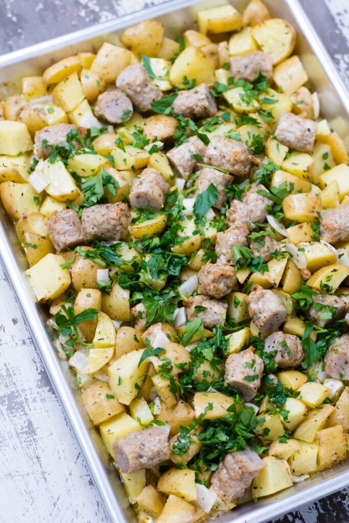 Seasoned potatoes, tender onions, and hearty sausage make this recipe for Baked Breakfast Potatoes with Sausage is a true crowd-pleaser. Breakfast potatoes and sausage topped with parsley.