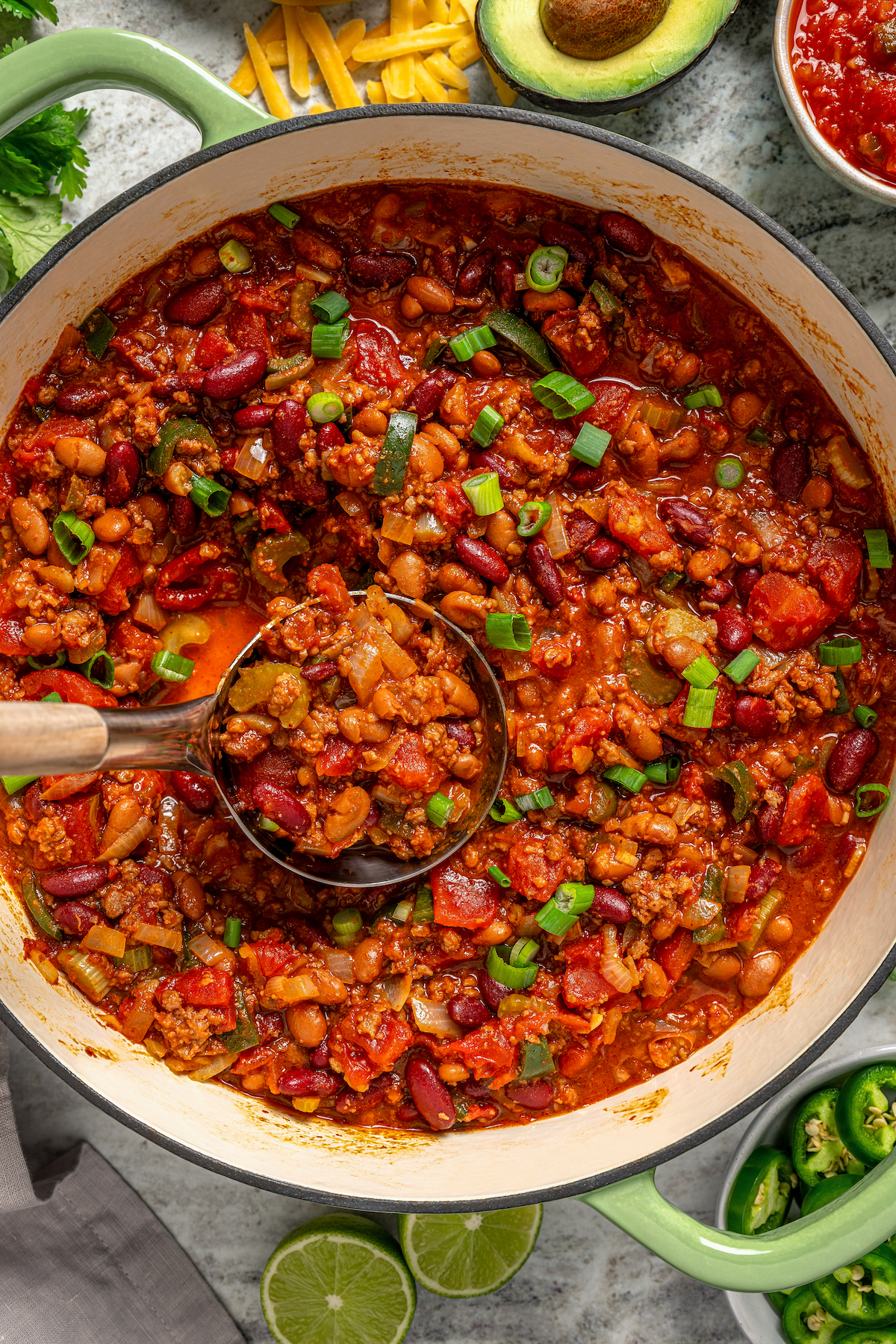 This freezer-friendly turkey chili recipe with beans, bell peppers, onions, and tomatoes is a smokey and spicy Tex-Mex weeknight dinner. Grabbing a spoonful of the chunky turkey chili.