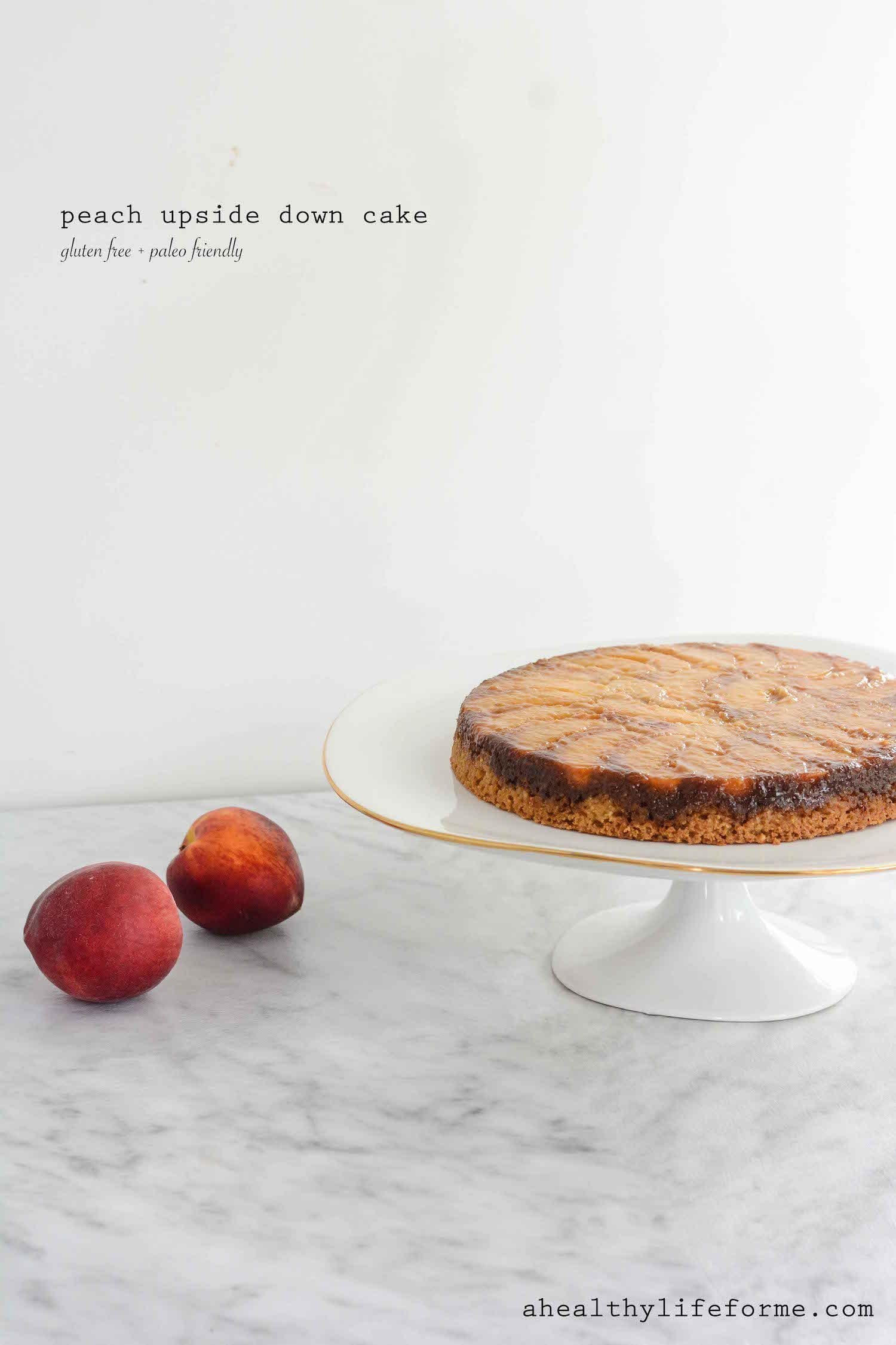 A whole peach upside down cake on a white cake stand. 