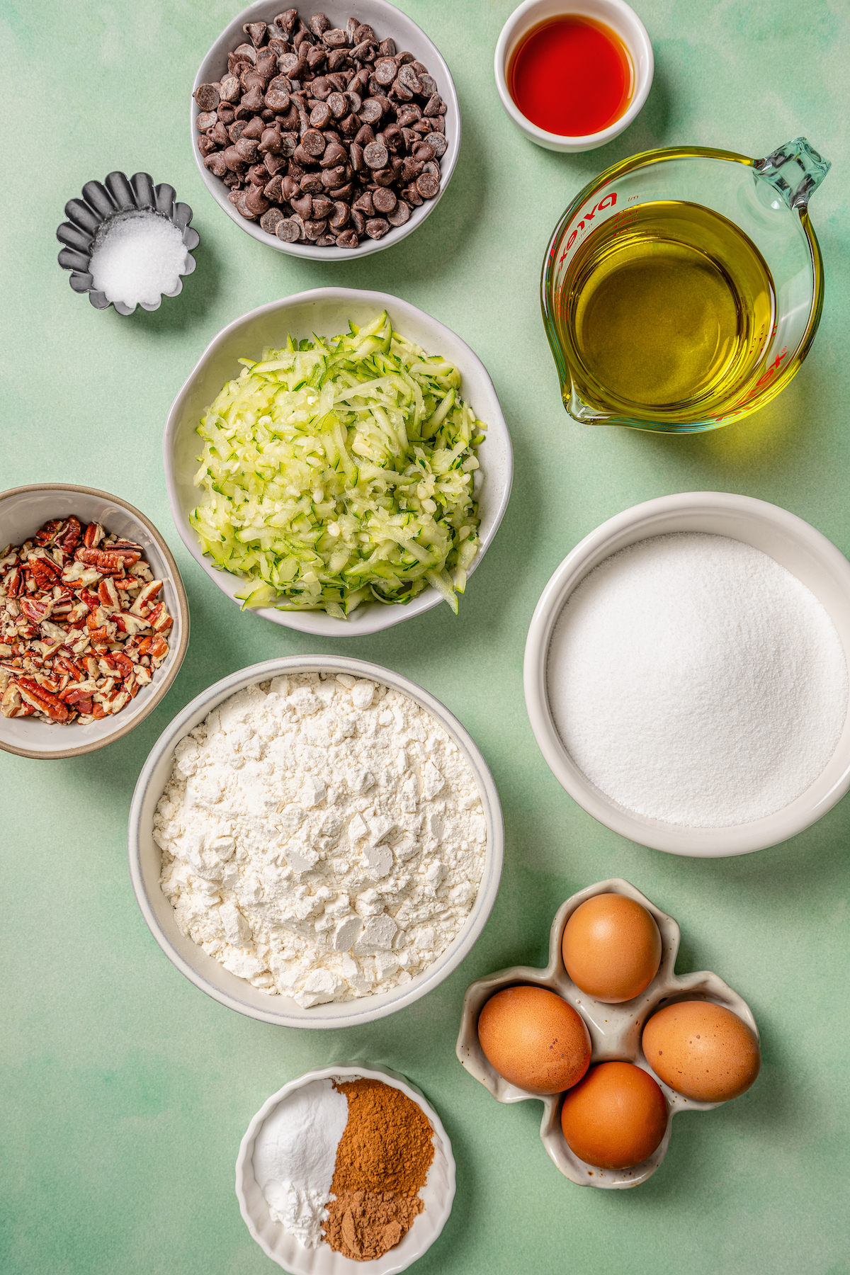 This tender zucchini bread recipe with cinnamon, earthy nutmeg, and semi-sweet chocolate chips is an easy way to sneak veggies into dessert. Labeled ingredients for making zucchini bread.