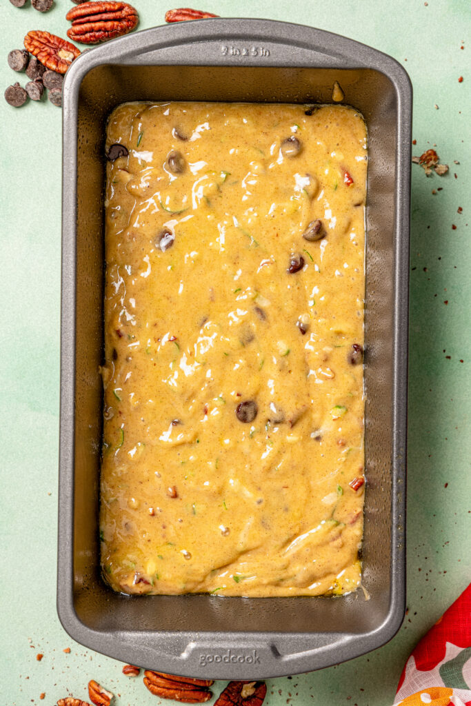 This tender zucchini bread recipe with cinnamon, earthy nutmeg, and semi-sweet chocolate chips is an easy way to sneak veggies into dessert. Batter in the prepared loaf pan.