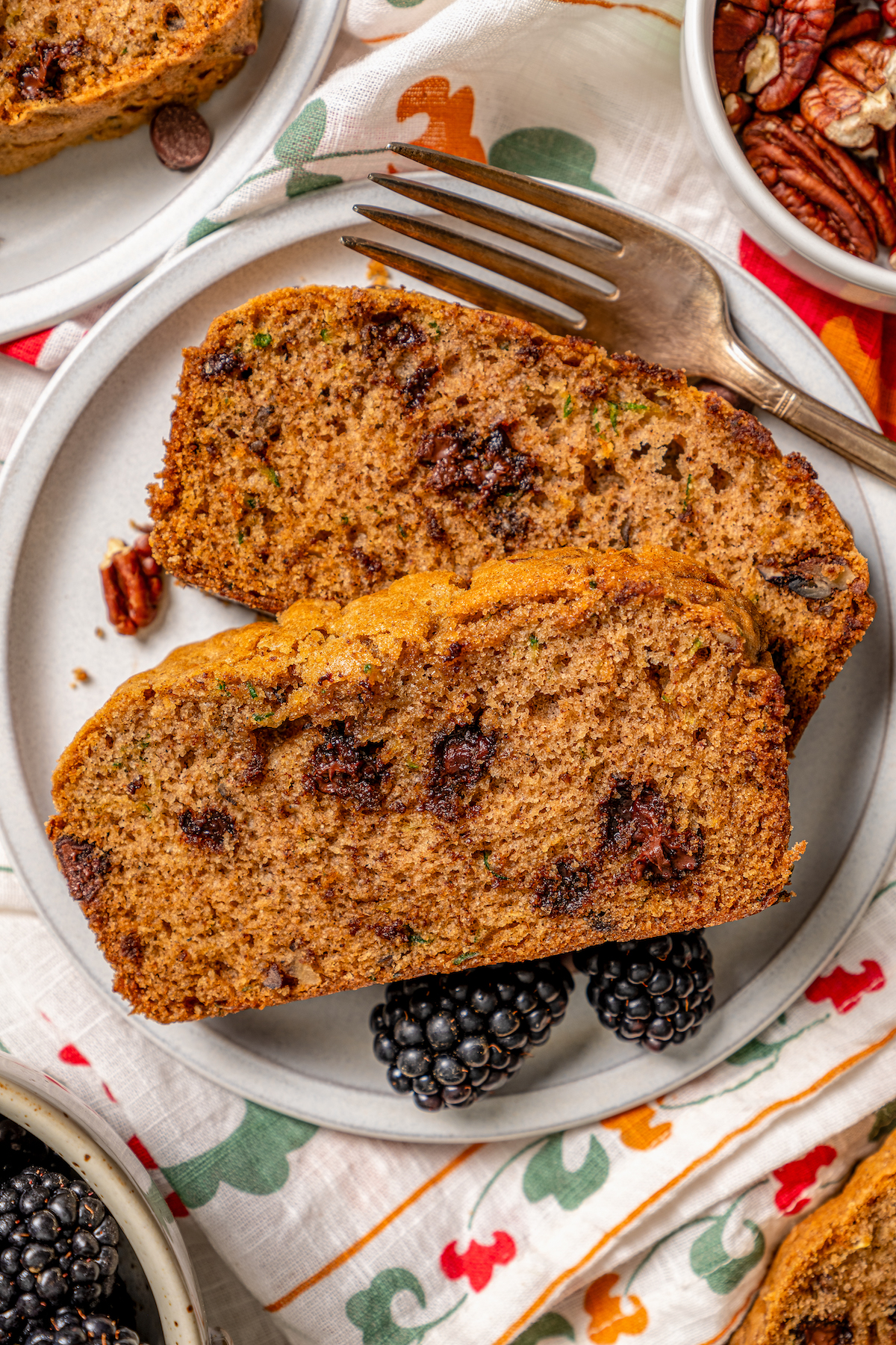 This tender zucchini bread recipe with cinnamon, earthy nutmeg, and semi-sweet chocolate chips is an easy way to sneak veggies into dessert. Fluffy, sliced zucchini bread with gooey chocolate chips.